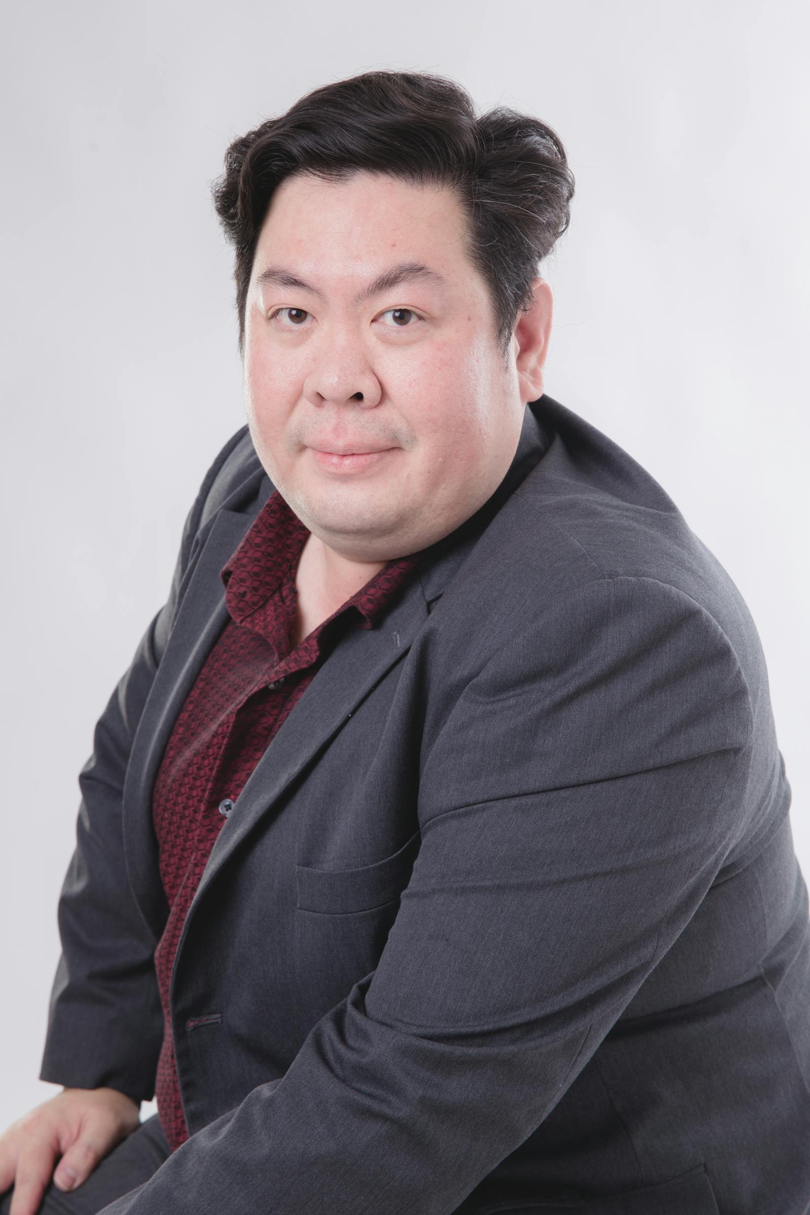 Studio portrait of Tomas Brivón, founder, in a grey overcoat against a Brooklyn brick wall.